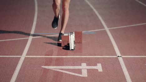 Front-view-of-a-female-athlete-starting-her-sprint-on-a-running-track.-Runner-taking-off-from-the-starting-blocks-on-running-track.-Zoom-camera.-Slow-motion